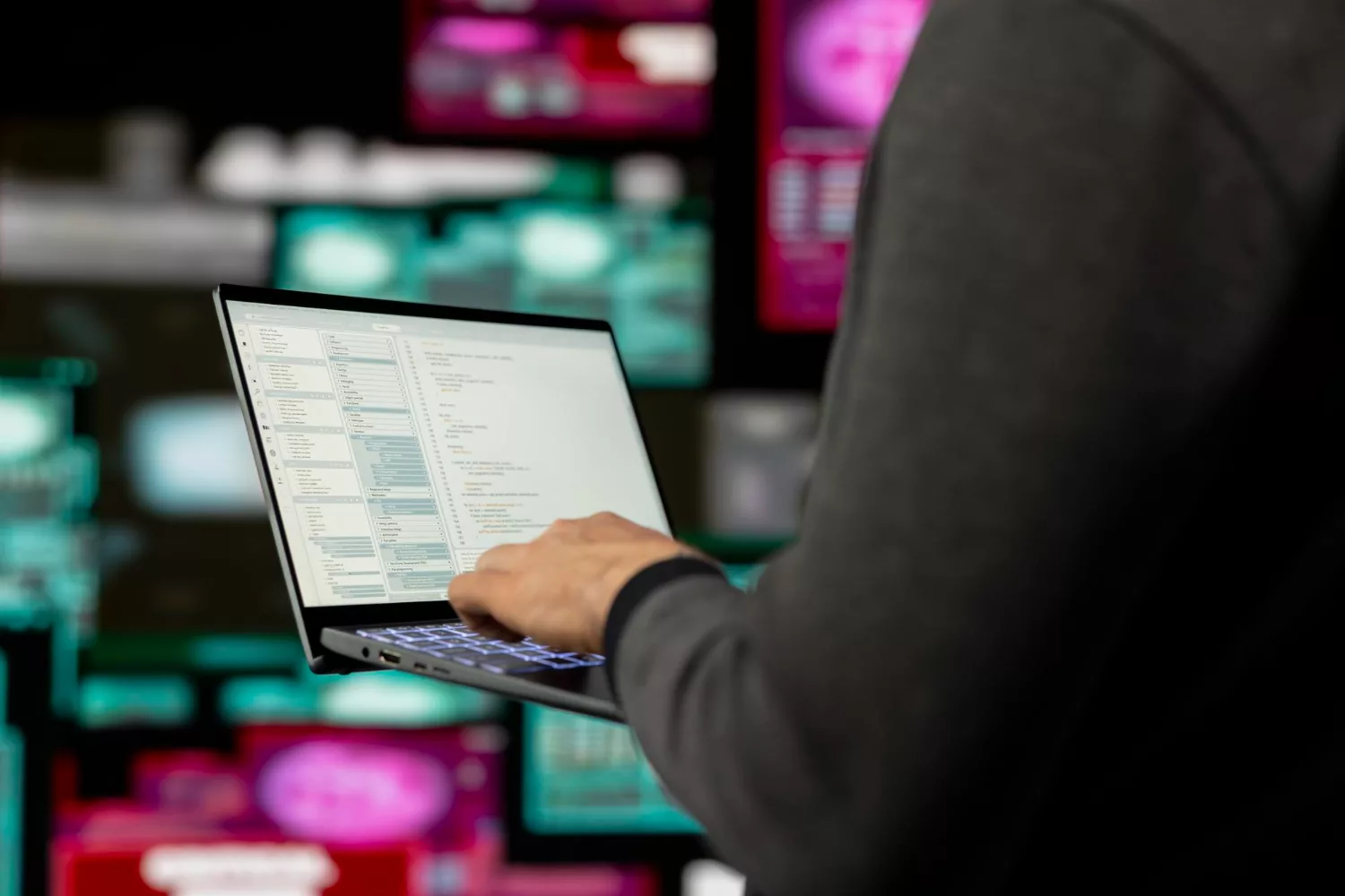Person using a laptop with digital data screens, illustrating cyber background checks in action.