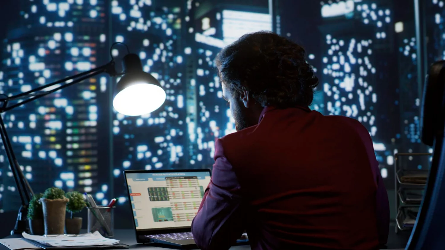 A professional analyzing cyber security certifications data on a laptop in a dimly lit office.