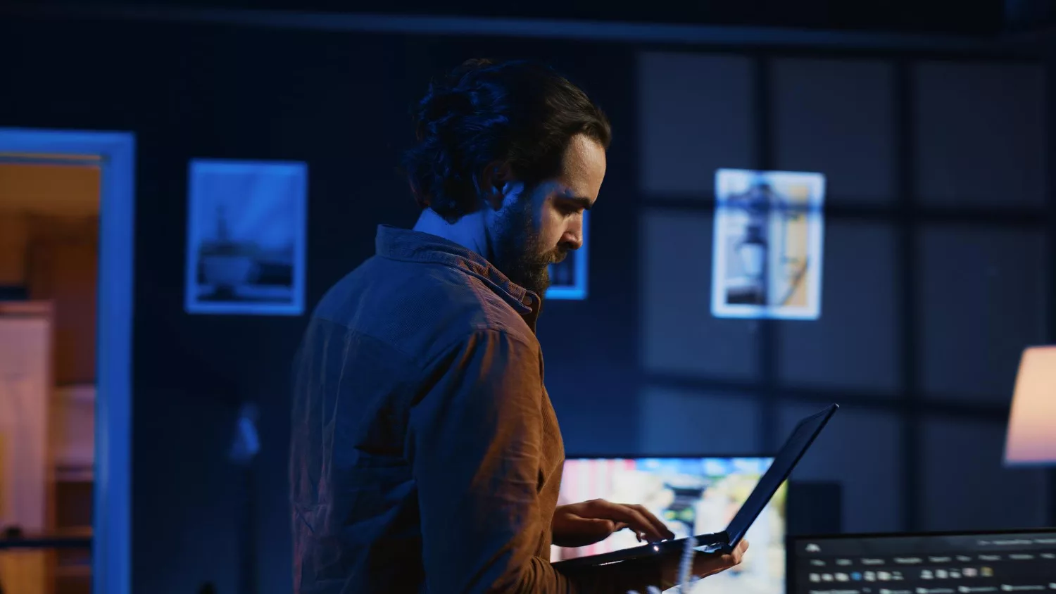 Man studying cyber security certifications on a laptop in a dimly lit room.