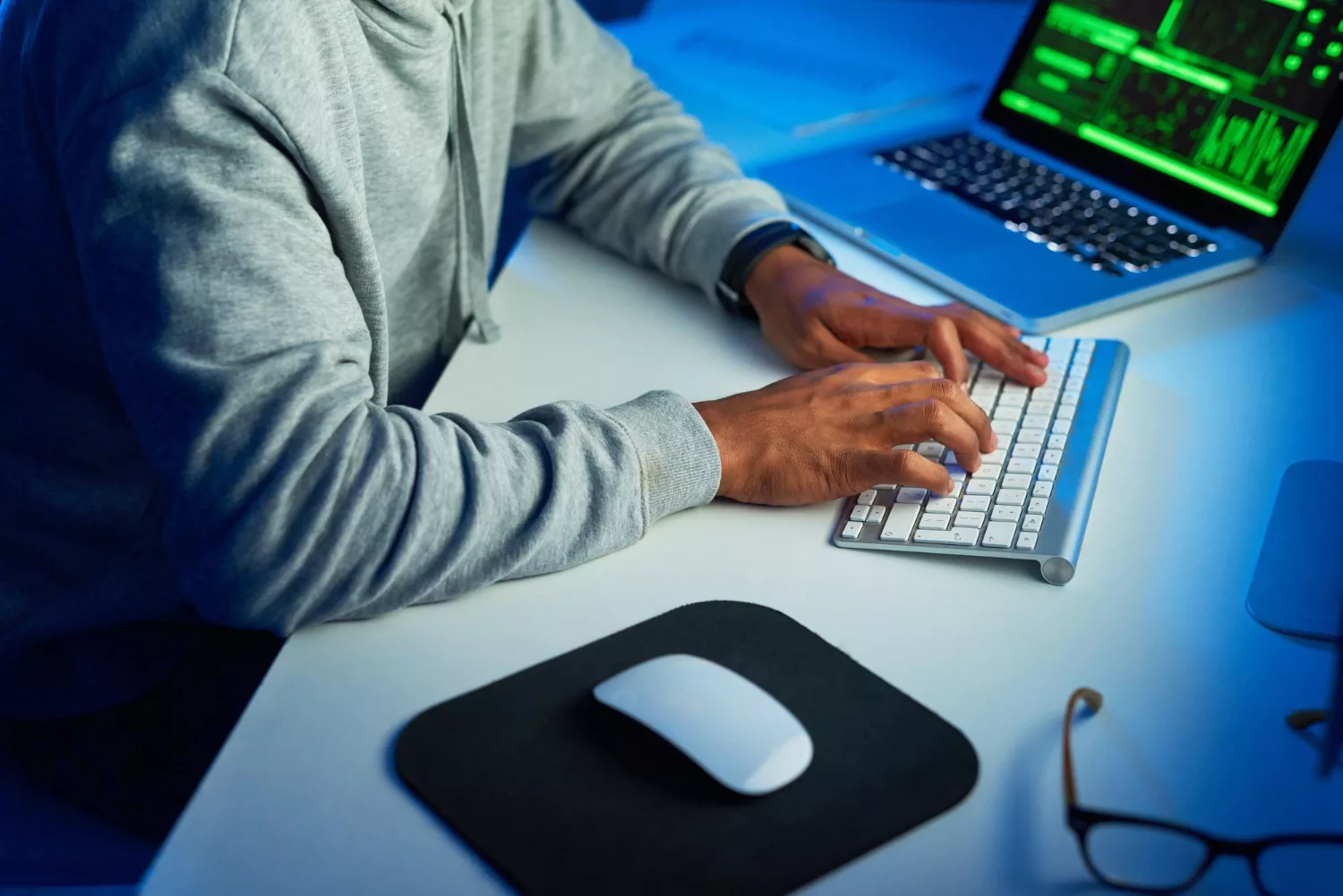 Person typing on a keyboard with code on a laptop, illustrating cyber security solutions in a business setting.