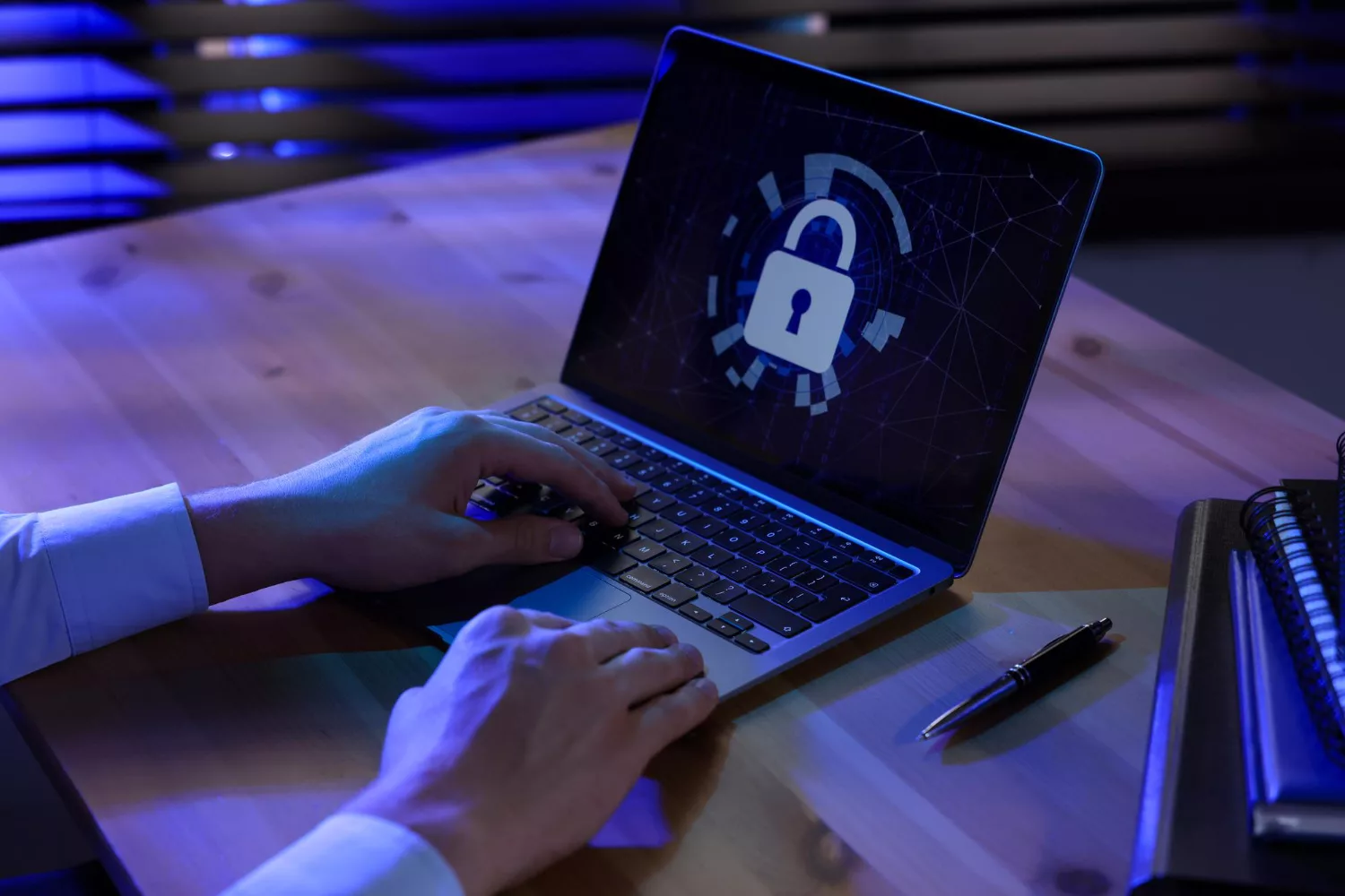 Person typing on a keyboard with code on a laptop, illustrating cyber security solutions in a business setting.