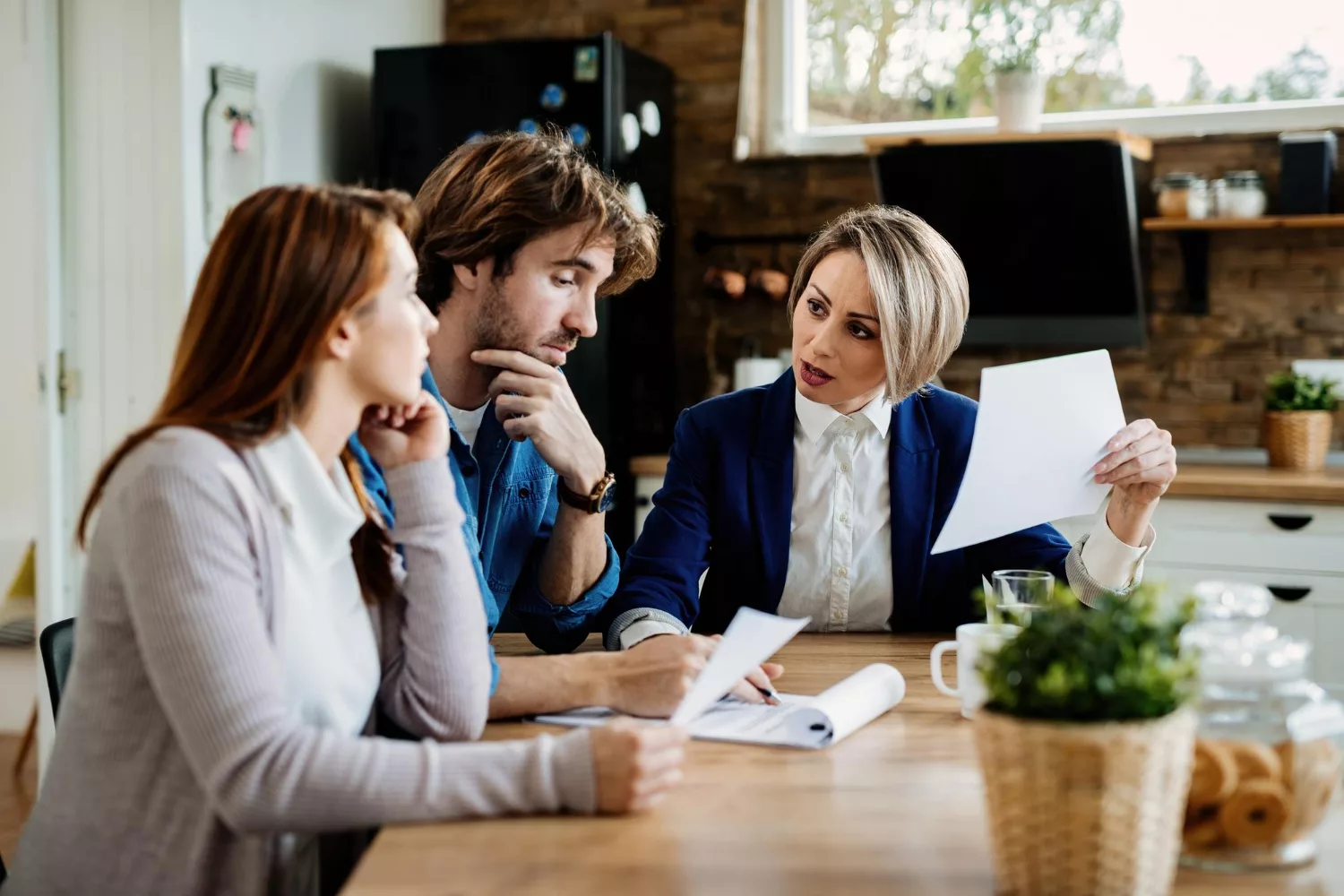 A professional explaining professional liability (E&O) insurance vs general liability to a couple at a table.