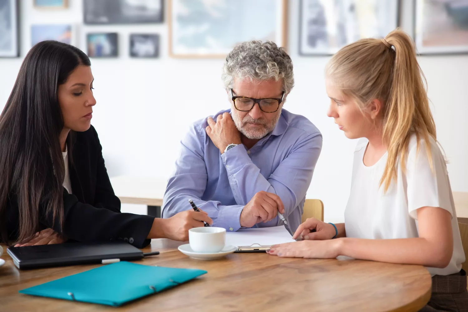 Three professionals discussing documents at a table, illustrating differences in professional liability (E&O) insurance vs general liability.
