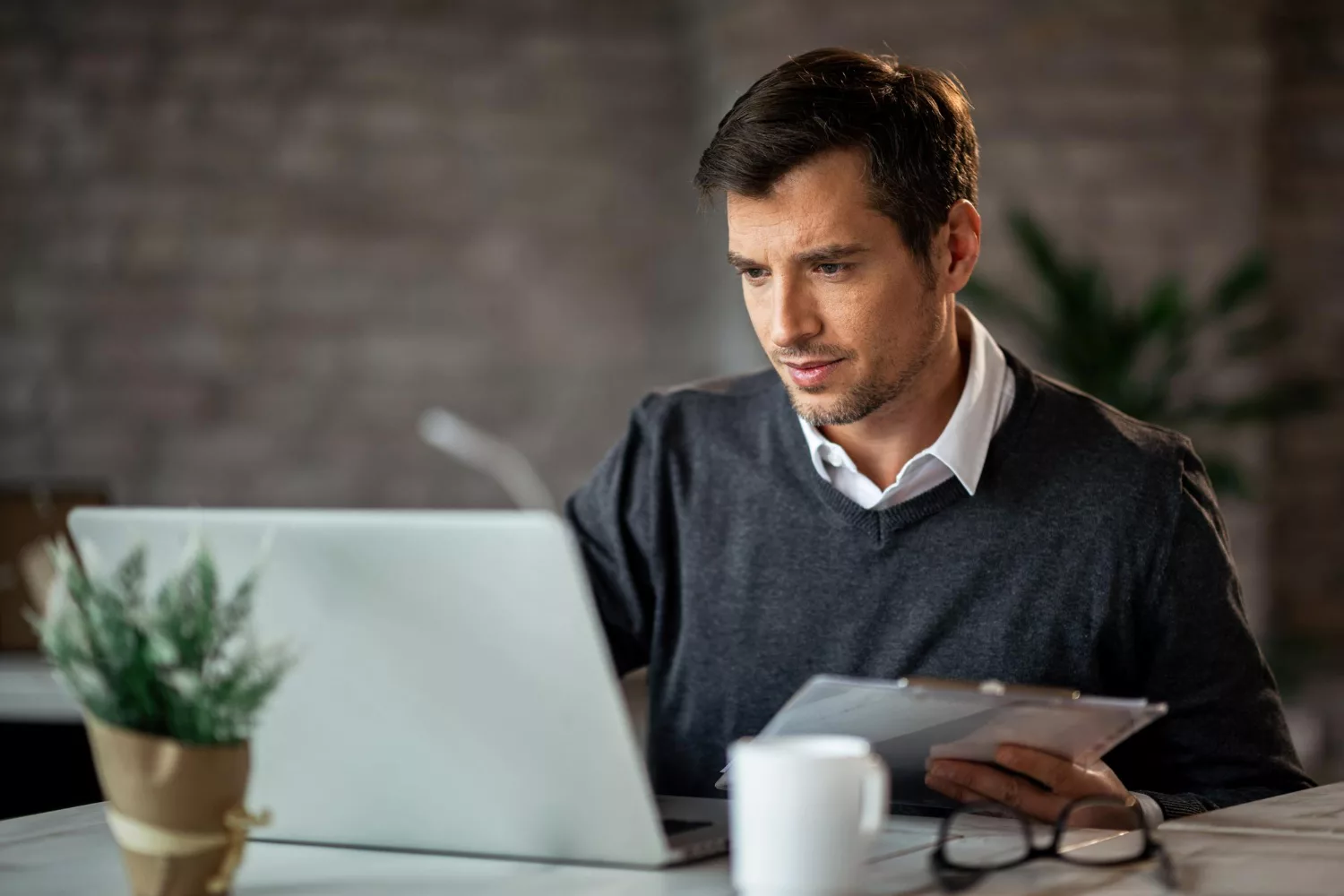 Man analyzing cyber liability insurance cost on laptop at home office.