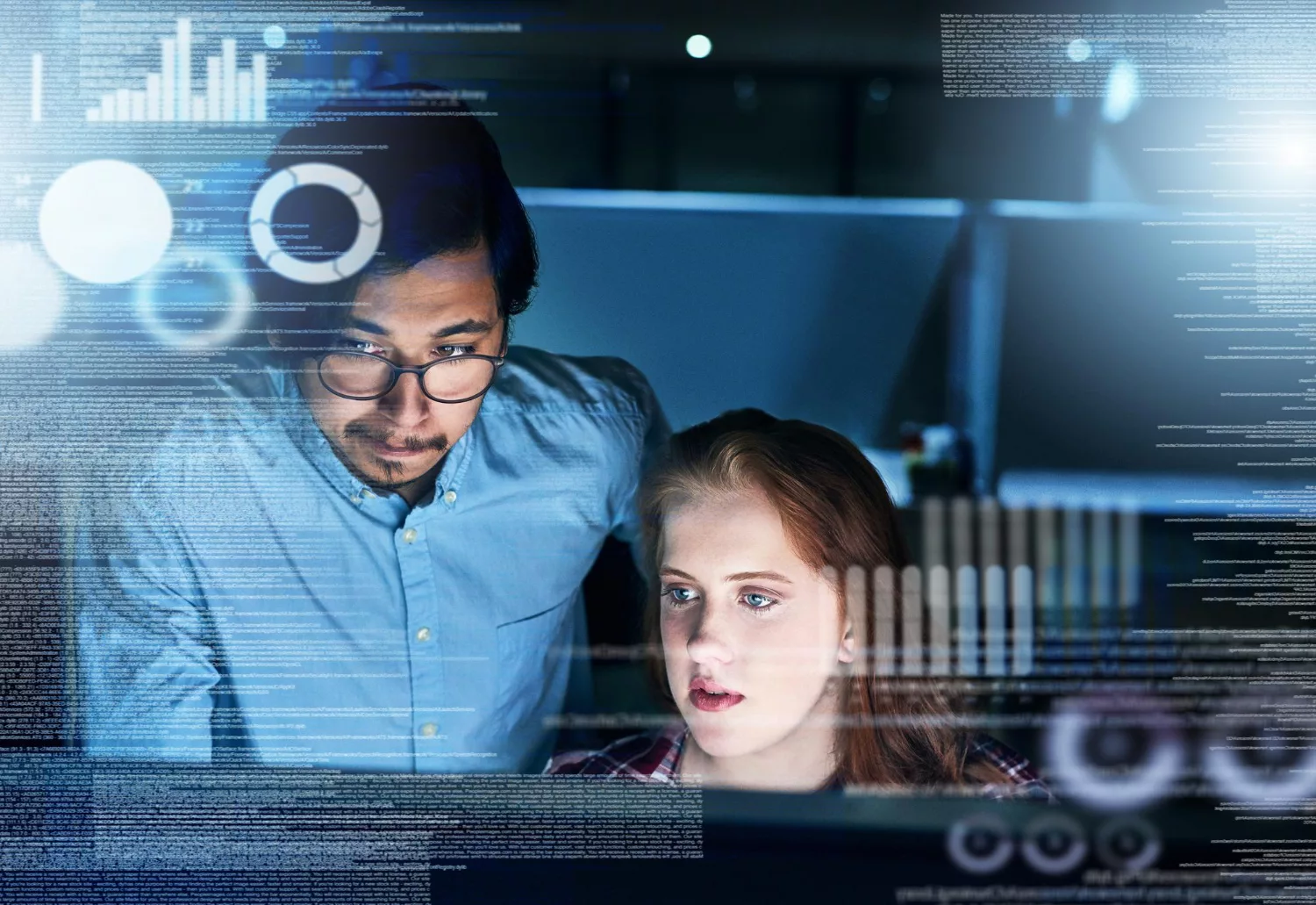 Two professionals analyzing data on a computer screen, illustrating what is cyber liability insurance.