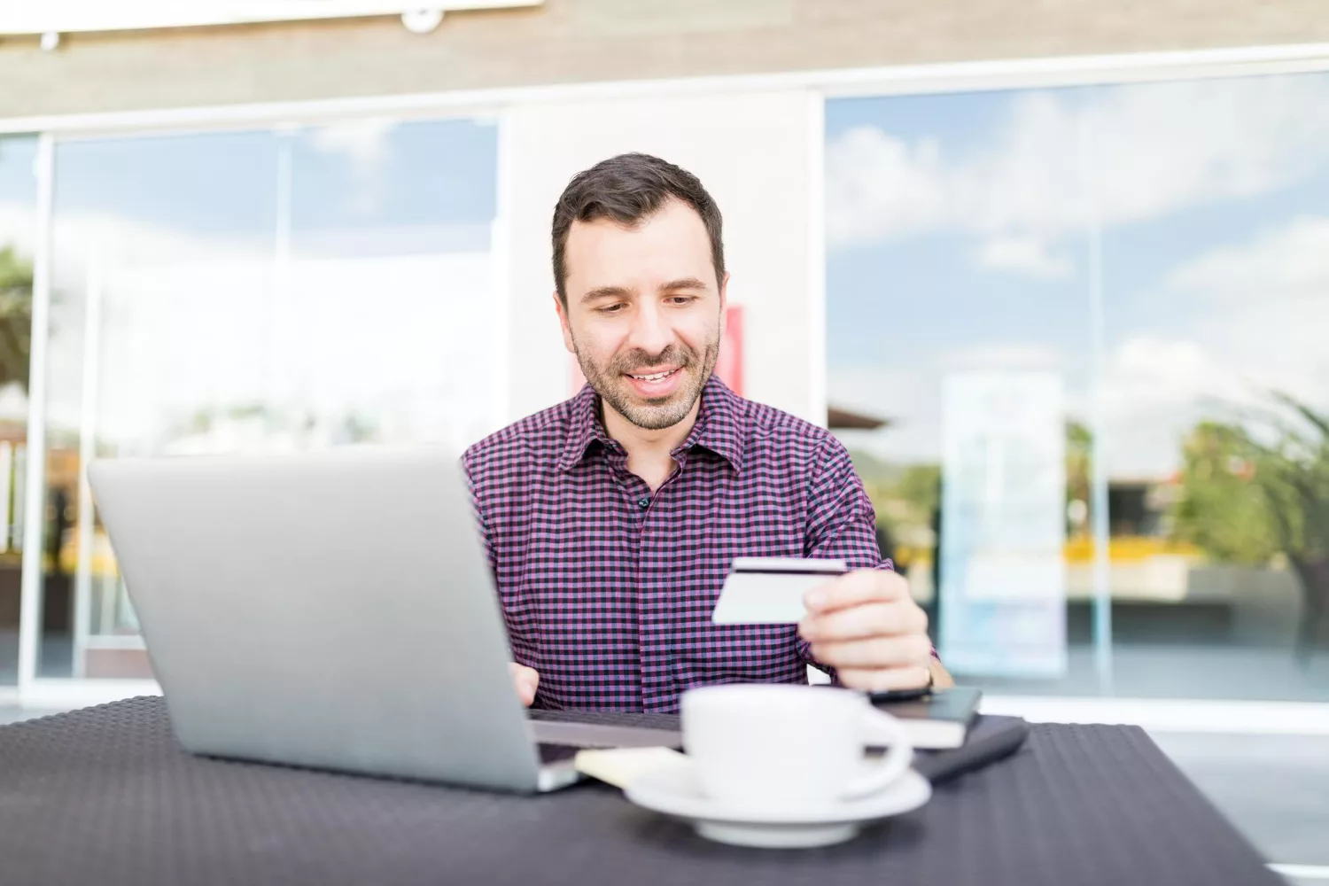 Man budgeting business insurance for startups on laptop with credit card and coffee.