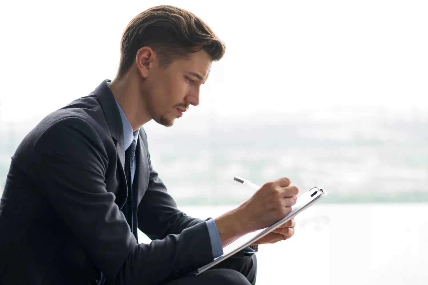 Business professional reviewing documents on clipboard, highlighting business insurance requirements for startups.