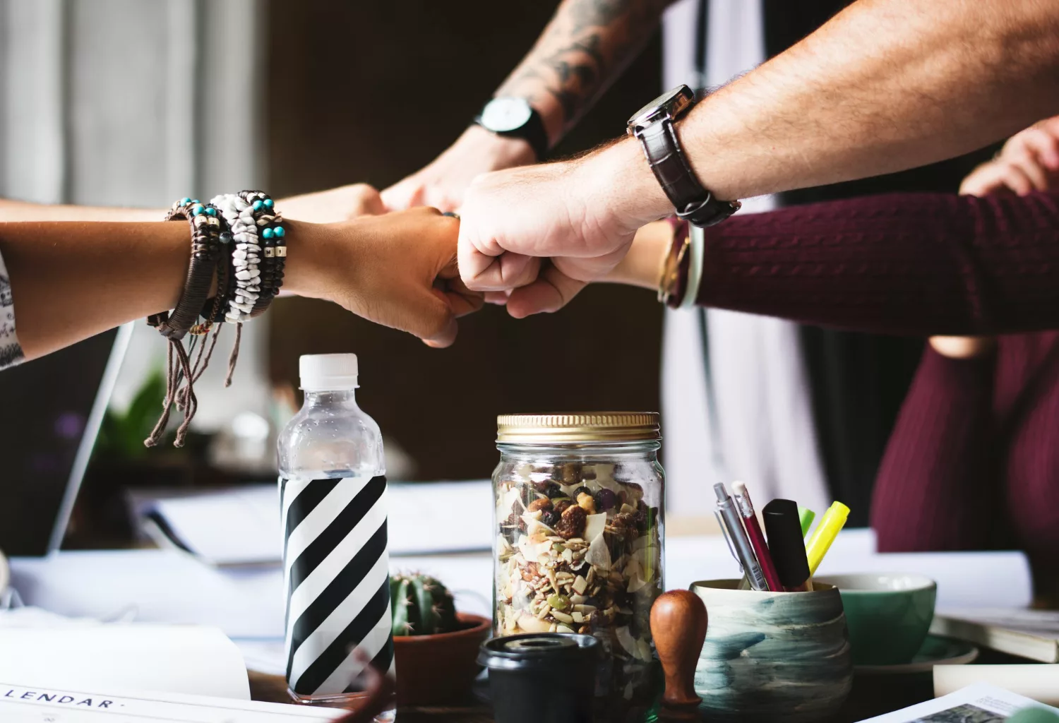 Team members doing a fist bump over a desk during a meeting about low-budget search strategies for nonprofit growth.