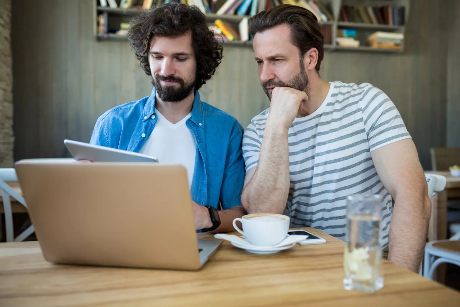 Two men reviewing content on a tablet beside a laptop, representing how SEO advantages and disadvantages have evolved from 2016 to 2026.